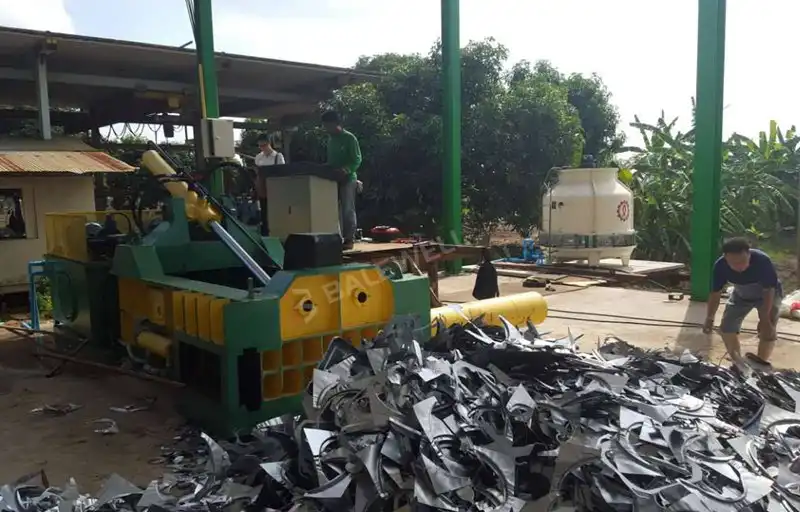 A BALEWELL metal baler in operation in Thailand, compressing scrap metal with a powerful hydraulic system.