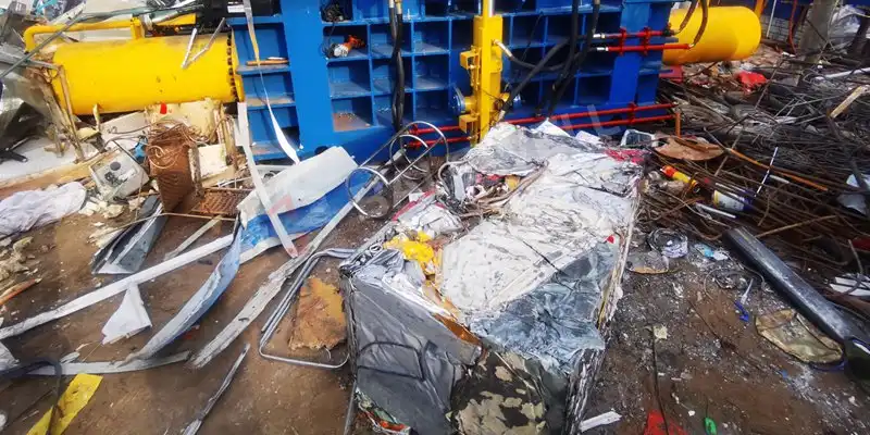Close-up of the MBK-315 metal baler in operation, compacting scrap metal into dense bales.